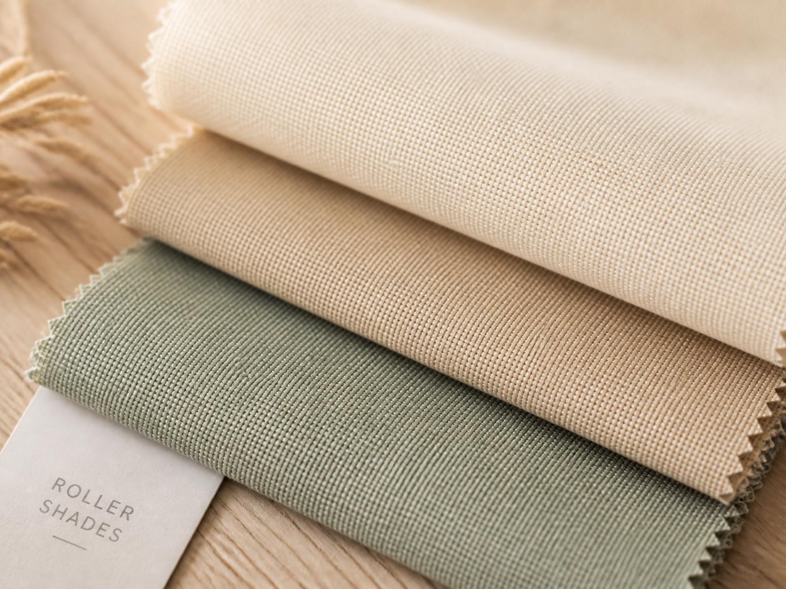 Cream, sand and sage roller shade fabric swatches on light oak